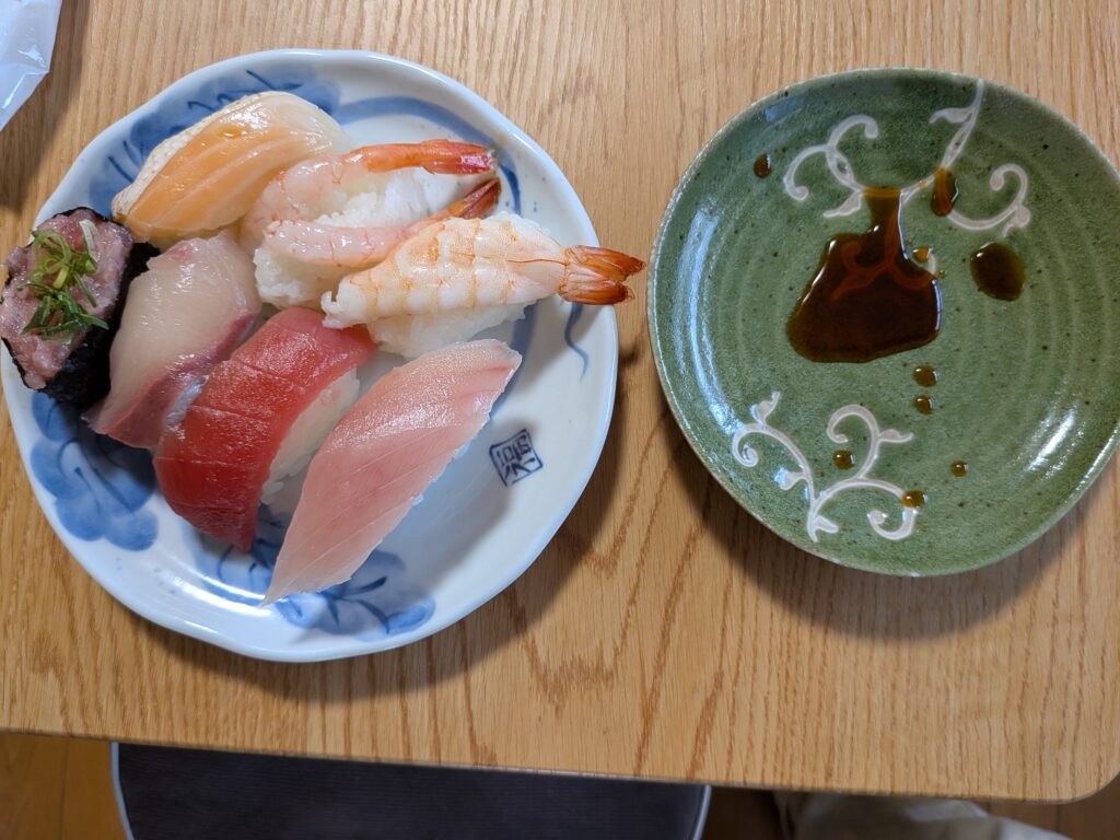 34日目 昼食:まぐろ・サーモン・ハマチ・エビなど 8 貫の握り寿司と醤油皿