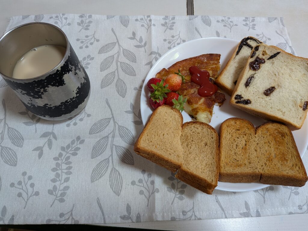 35日目 朝食:ベースブレッドトースト4切・レーズン食パン・チョコ食パン・チーズポテト・いちご・無糖カフェオレが並ぶ皿とマグカップ
